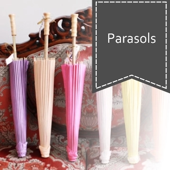 Assorted colorful parasols with wooden handles displayed upright on a vintage red and white patterned sofa.